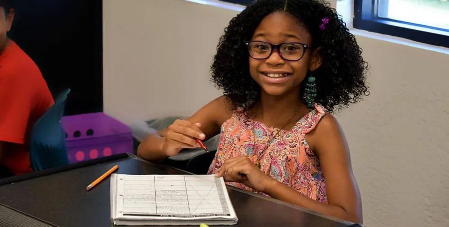 Élève souriante installée à sa table