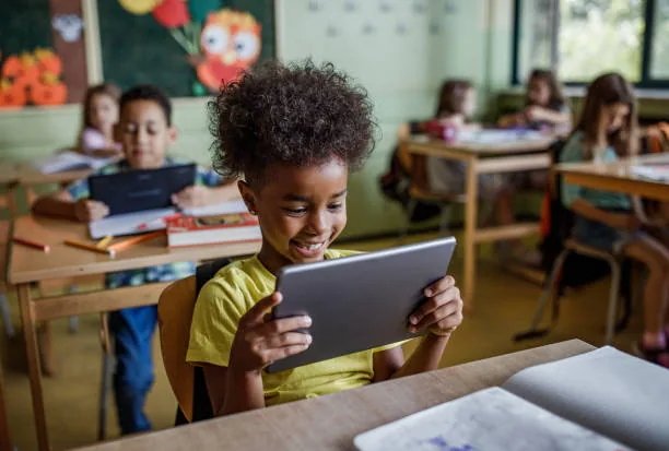 Élève souriante qui travaille sur une tablette en classe